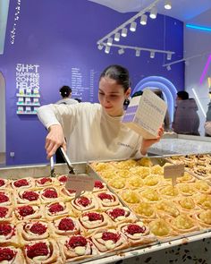 a woman standing in front of a table filled with pastries