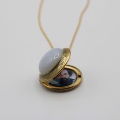 "This locket features a stunning glass moonstone surrounded by gold enamel. It opens to hold two photographs. ~Locket is stainless steel plated gold 1\" ~Gold plated brass chain ~Hand enameled" Brass Oval Pendant Jewelry For Keepsake, Antique Gold Locket Jewelry For Keepsake, Antique Gold Keepsake Locket Jewelry, Brass Locket Jewelry For Keepsake, Keepsake Yellow Gold Brass Locket Necklace, Keepsake Yellow Gold Locket Necklace In Brass, Antique Gold Keepsake Necklace, Yellow Gold Brass Locket Necklace For Keepsake, Antique Gold Keepsake Round Pendant Jewelry