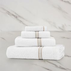 four white towels stacked on top of each other in front of a marble countertop