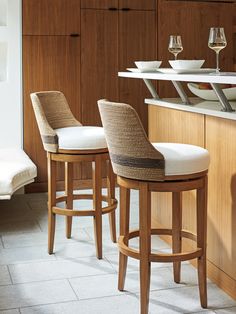 two bar stools sitting next to each other in front of a counter with wine glasses on it