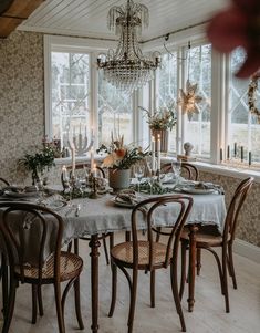 a dining room table is set with place settings and candles in front of the windows