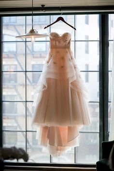 a dress hanging on a hanger in front of a window