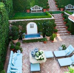 an outdoor patio with seating and potted plants in the center, surrounded by hedges