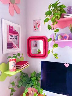 a desk with a computer, potted plant and pictures on the wall