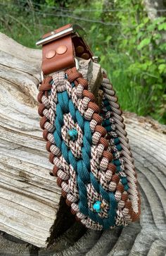 a brown and blue bracelet on top of a piece of wood next to a tree