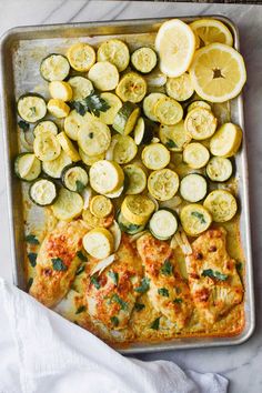 a pan filled with chicken, squash and zucchini on top of a table