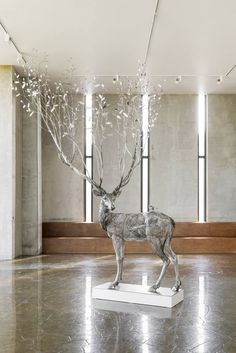 a statue of a deer with branches in it's antlers is on display