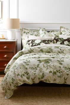 a bed with white and green floral comforter set on top of a brown rug