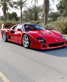 a red sports car is parked on the side of the road in front of palm trees