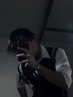 a man taking a selfie with his cell phone in the dark, while wearing suspenders