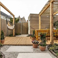 a wooden deck with potted plants and hammock hanging from it's sides