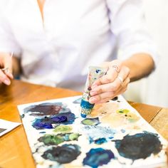 a woman is painting on a piece of paper