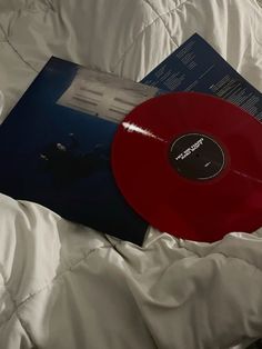 a red record sitting on top of a white bed