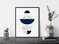 a black and white art print sitting on top of a table next to a potted plant