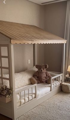 a teddy bear sitting on top of a white bed in a room next to a window