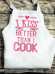 a white apron that says i kiss better than i cook