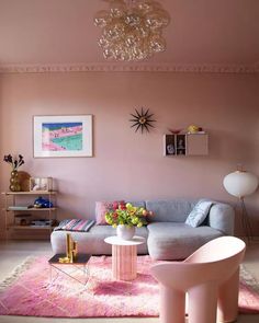 a living room filled with furniture and a chandelier hanging from the ceiling over a pink rug