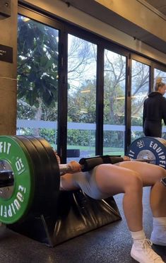 a woman sitting on top of a bench holding a barbell