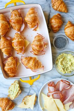 croissants, ham and cheese are on a tray next to other food