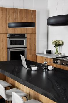 a modern kitchen with black counter tops and white chairs