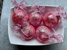 pink glittered christmas ornaments on a white plate