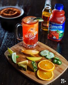 a wooden cutting board topped with sliced oranges and cucumbers next to bottles of alcohol