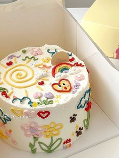 a decorated cake in a white box on top of a table next to other items