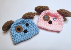 two crocheted hats with brown ears and nose are on a white surface, next to each other