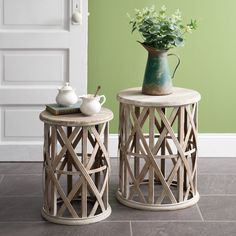 two tables with vases on them sitting next to each other in front of a green wall