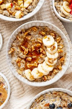 oatmeal with bananas and blueberries in bowls on a table top next to other breakfast foods