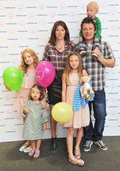 a family poses for a photo in front of a wall with balloons