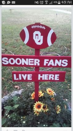 a football sign with flowers in the foreground and another sign that says, sooner fans live here