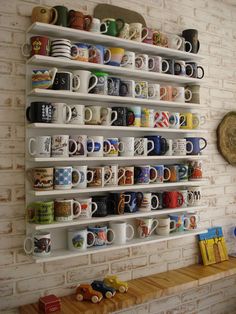 coffee mugs are lined up on the wall behind a shelf with shelves full of cups