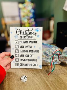 a person holding up a christmas gift exchange card with dice on the table next to it