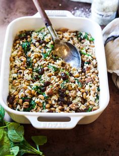 a white casserole dish filled with rice, beans and spinach topped with a spoon