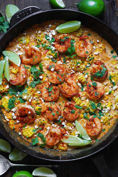 a skillet filled with shrimp, corn and cilantro on top of a wooden table