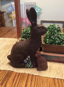 a statue of a rabbit sitting on top of a rug next to a potted plant