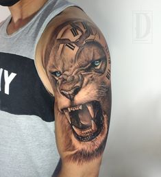 a man with a tattoo on his arm has a lion clock in it's mouth