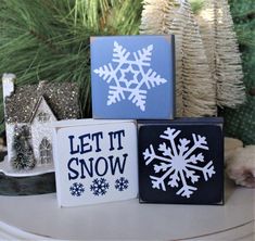 three snowflakes are sitting on a table next to some christmas tree branches and other decorations