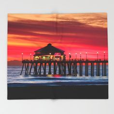 a colorful sunset over the ocean with a pier in the foreground