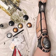 a woman's leg with tattoos and makeup tools on the ground next to it