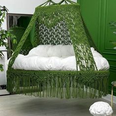 a green bed with white pillows in a room next to a chair and potted plant