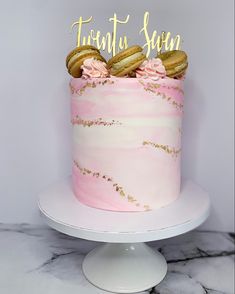 a pink and gold cake with cookies on top