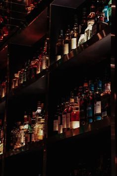 many bottles are on shelves in a dark room