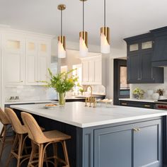 a large kitchen with an island and bar stools in the center, surrounded by blue cabinets