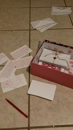 an open box on the floor with papers scattered around it and a red pencil laying next to it