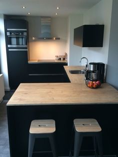 a kitchen with two stools next to an island