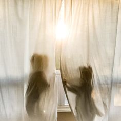 a blurry image of a person standing in front of a window with curtains open