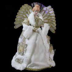 an angel doll holding a fan and wearing a white dress with gold trimmings