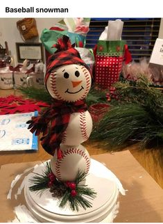 a baseball snowman sitting on top of a white base covered in red and black ribbon